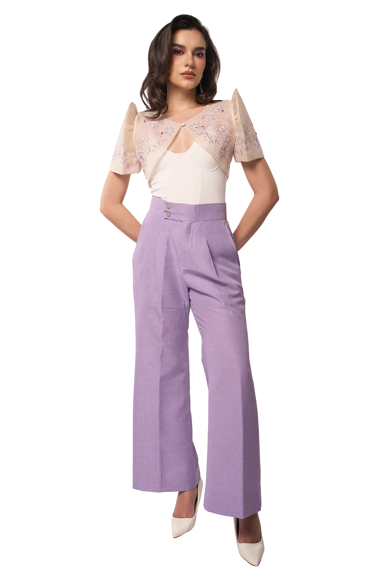 Woman wearing a white top with lace details and purple pants on a white background
