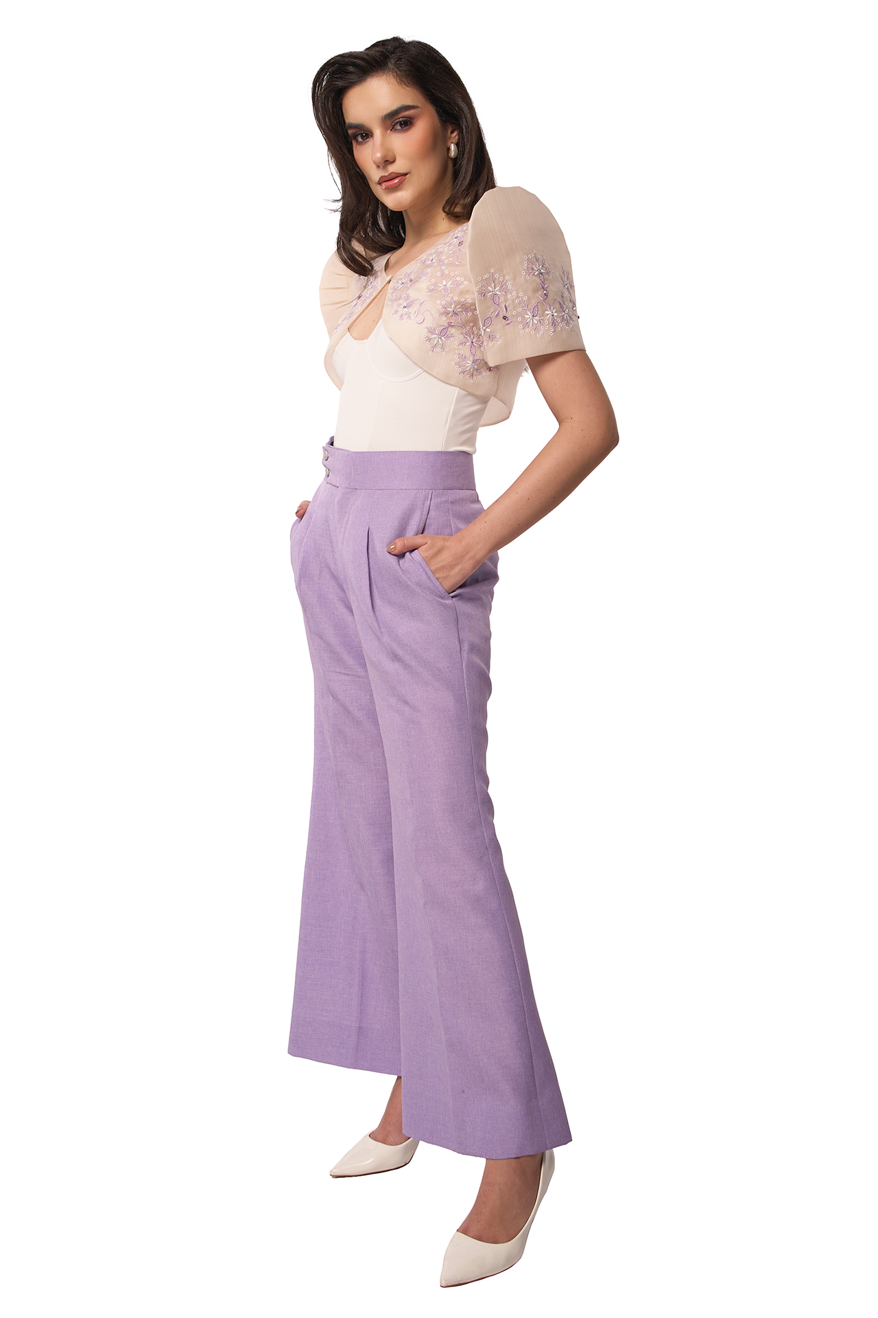 Woman wearing a white top with floral sleeves and purple pants on a white background